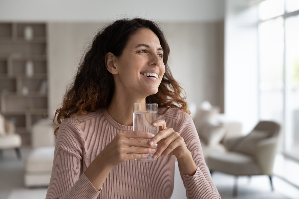 Frau hält ein Wasserglas und lacht