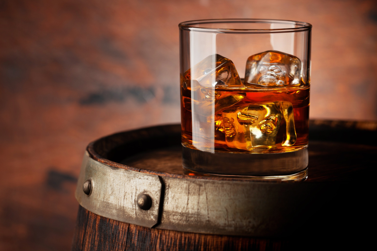 Whiskeyglas auf einem Holzfass