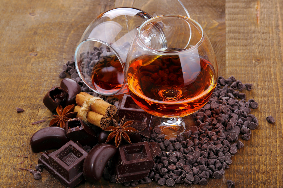 Glas Cognac und Schokolade auf rustikalem Holztisch